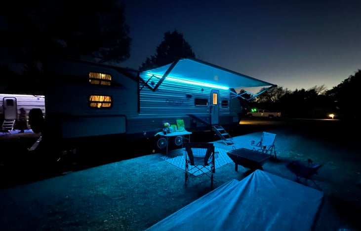 Camper at night with outdoor lighting.