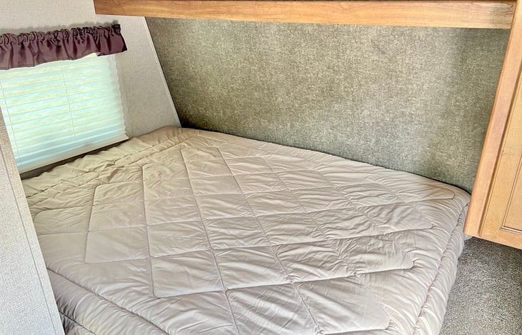 Queen size bed toward front of camper.