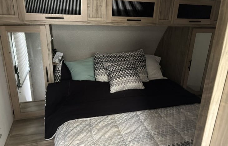 The bedroom is located in the front. Queen size bed with linens. Storage above and on each side. TV is mounted on wall with adjustable arm.