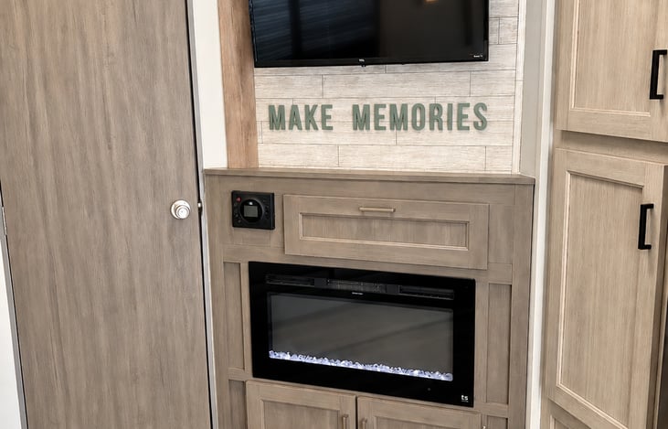 Cozy entertainment area featuring a large TV and electric fireplace — the perfect spot to relax and unwind after a day of adventure.