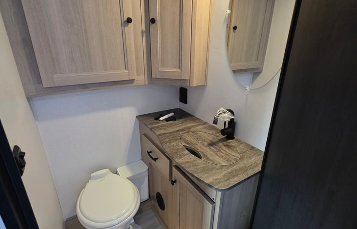Toilet Sink area with storage.  Door can close for privacy or be latched open to include the shower area.
