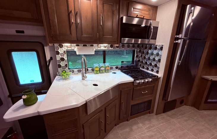 Fully equipped kitchen with a countertop extension, farmer’s sink, decorative tile splash and extra cabinet space.