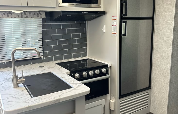 Kitchen includes oven, gas cooktop, fridge, freezer, microwave, cookware and a coffee pot as well as necessities like utensils, aluminum foil, storage bags, trash bags and cleaning supplies.