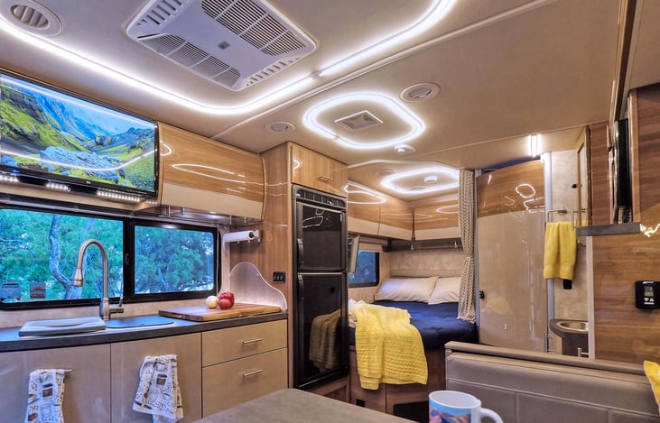 From dinette towards the bed. Kitchen with two burner stove and refrigerator on the left. Bathroom next to the queen bed.