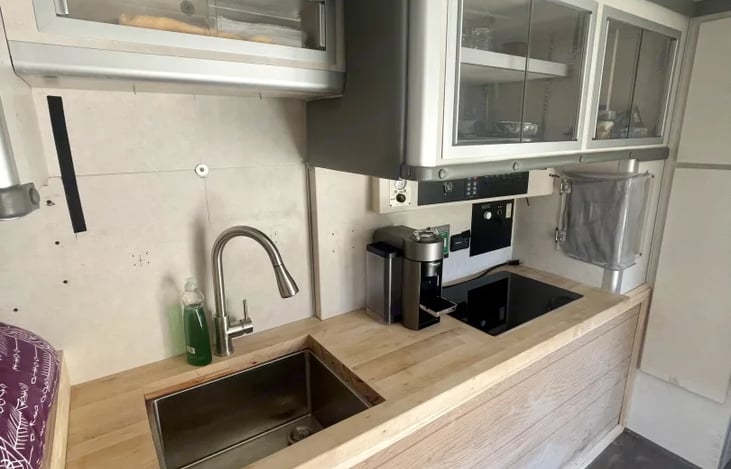 Cooking area with sink and induction cooktop

All dining and silverware in the compartments above

Nespresso Vertuo and communal pantry to the right
