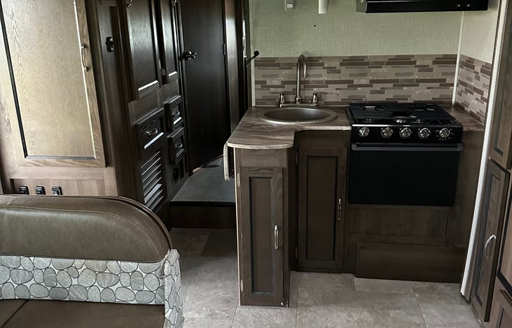 Compact kitchen area provides stove, microwave, refrigerator, and cooking utensils at your fingertips.