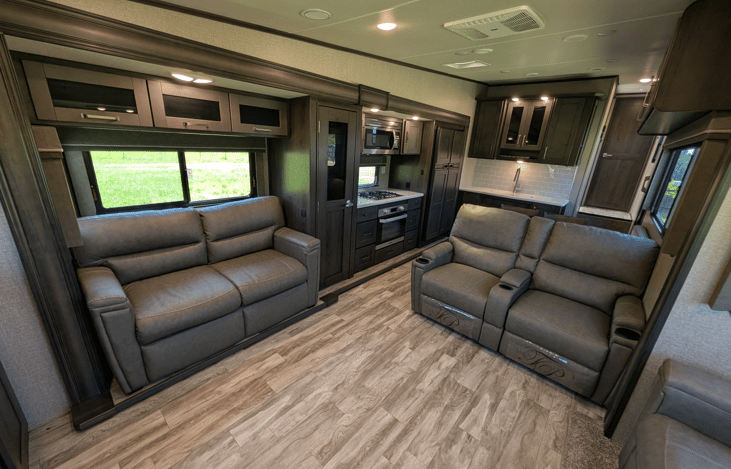 Gourmet galley & rear den retreat! Includes a 12 cu ft fridge, pantry, stove/oven, dual sofas, theater seats, 50" TV, electric fireplace, and 3 slides for spacious high-end living.