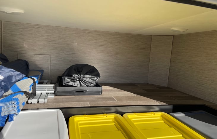Roomy outdoor storage can fit a  cooler, camping chairs, or luggage. Electrical and water hoses are neatly organized in labeled storage bins for easy access.