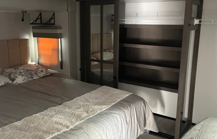 King size bed with lots of clothing storage. Featuring shelves, hanging racks, and small dresser.