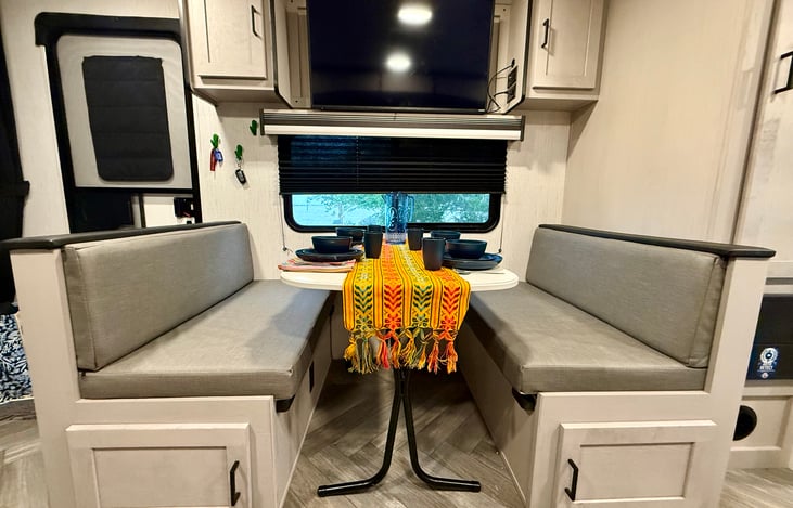Dining area that seats four and converts to a bed offering another sleeping arrangement. Mounted TV with extendable arm and surround sound to see and hear from all areas in the Campfire Casita.