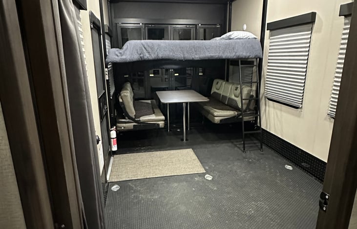 Looking from main area into 15' garage, 4-6 seat table with lighting(table doubles as a queen bed, queen upper bunk bed