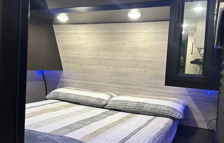 Primary Room with doors for privacy. This room features a queen bed, storage shelfs, rod for clothes, and two nightstands.