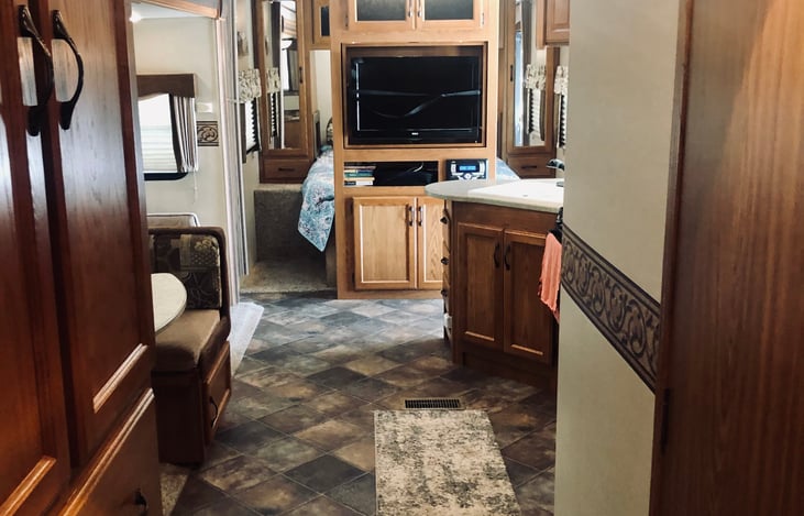 hallway storage on the left, bathroom door on the right, view facing kitchen/living area and behind TV is the queen bed with plush memory foam mattress, TV swivels for bedtime viewing...