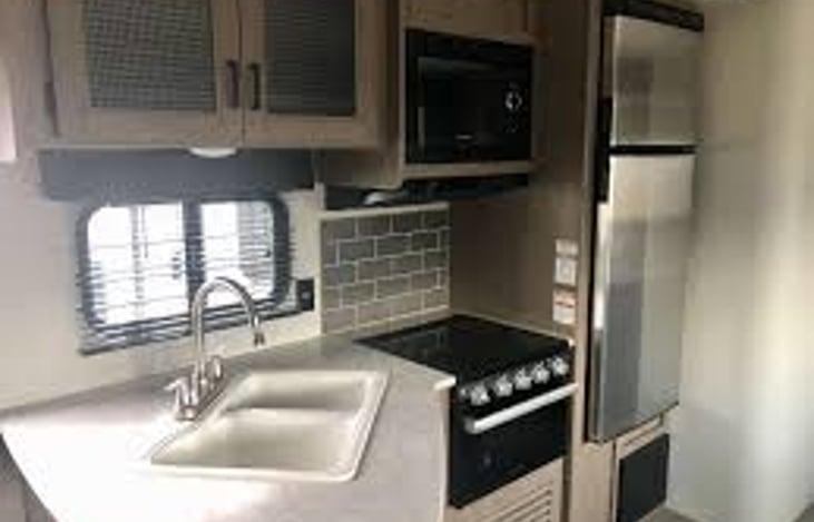 Indoor kitchen. Duel sinks, 4 burner stove, microwave and stainless steel fridge.