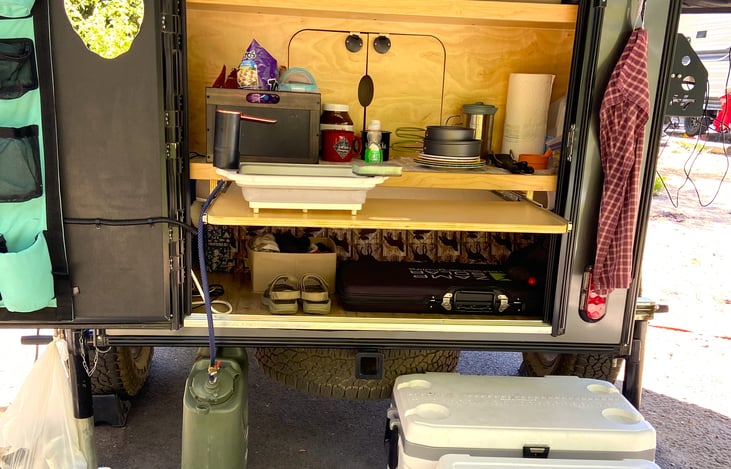 The kitchen area boasts a lot of features. You have storage space, prep space, a pass through to the main part of the camper and additional storage on the door.