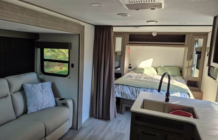 Modern luxury inside! Features a private master queen, double bunks, a huge U-shaped dinette slide-out, a fully loaded kitchen, a 10.2 cu ft fridge, a full bath, and premium JBL sound.