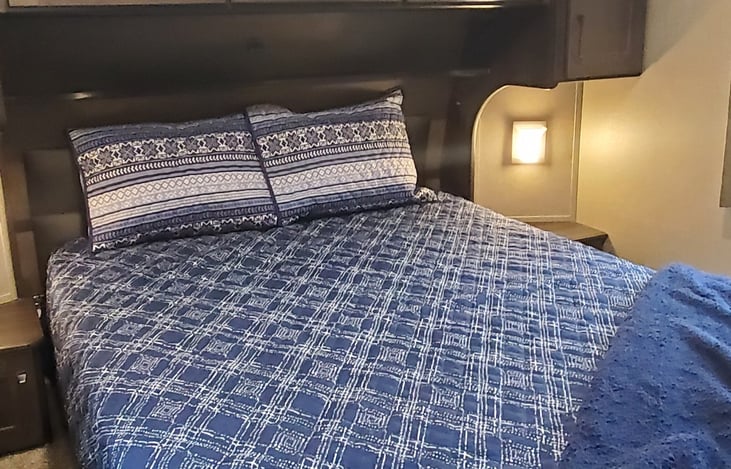 Residential queen size bed with overhead and side cabinets along with side lights and nightstands with storage