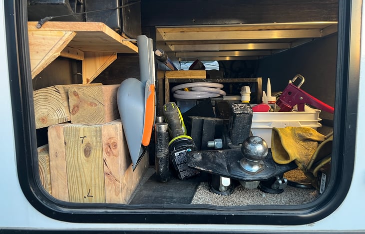 Pass through storage containing hitch, anti-sway bars, wheel chocks, leveling blocks, water hoses, etc.
