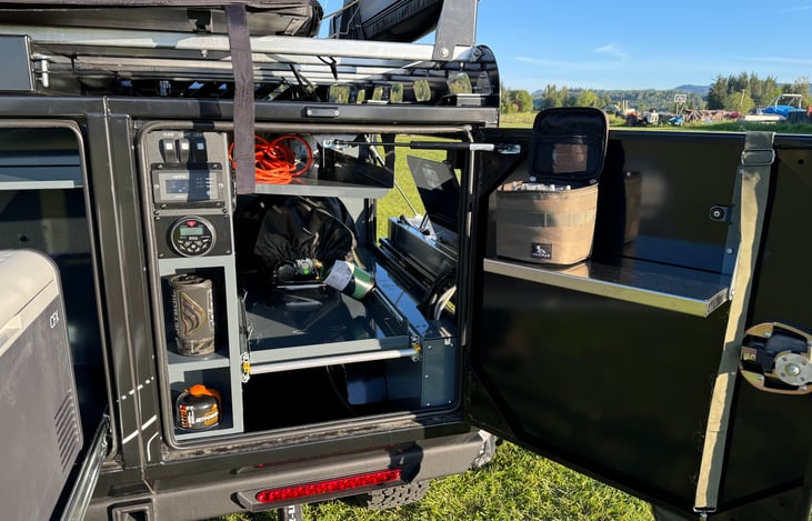 Rear storage compartment with BBQ on slide out. Inverter monitor, water pump and lighting switches.  The controls for the bluetooth stereo is also located here.