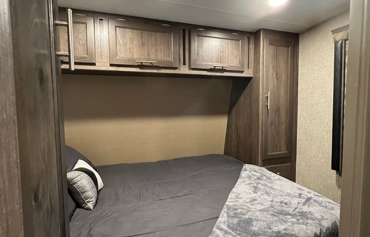 Master suite view from bathroom. Features two reach-in closets with hangers, overhead storage, under bed storage, bedside drawers, bedside USB charging dock and automatic Maxxair fan.