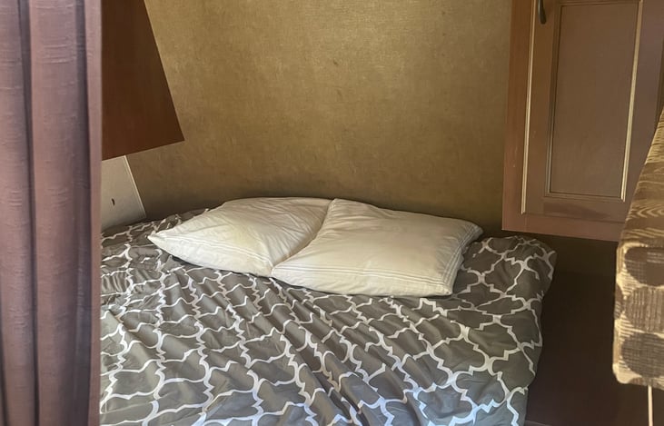 Located at the front of the trailer: Large separate queen bed with TV mounted to wall with curtains you can pull.