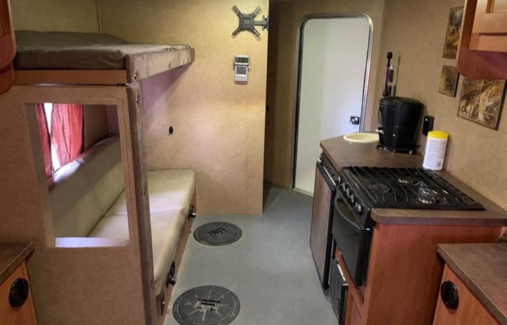 Interior of camper when standing and facing the exterior door
- Fold-out jackknife sofa bed
- Bunk bed above
- Mini fridge, propane gas stove/oven, coffee maker, air fryer, kitchen supplies
