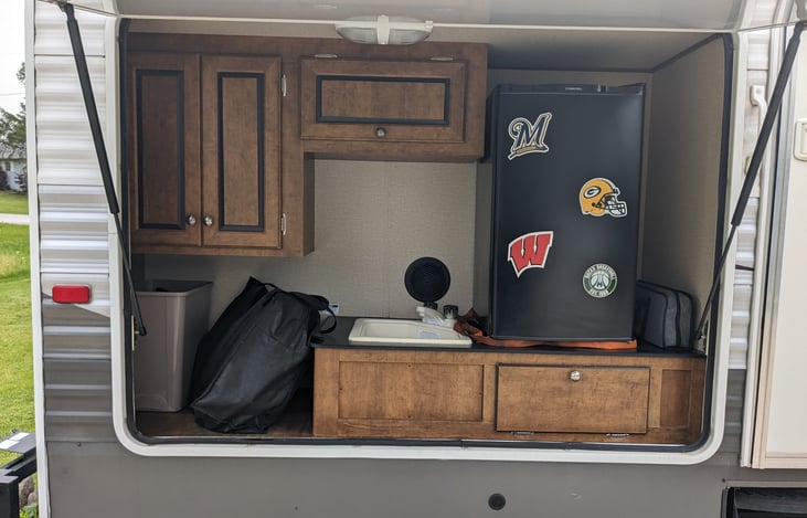 Outdoor kitchen with sink and fridge, along with more storage and hard plumbed gas grill that comes with every rental.