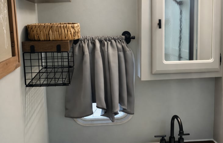 Bright vanity area with mirror lighting, storage shelves, and countertop space.