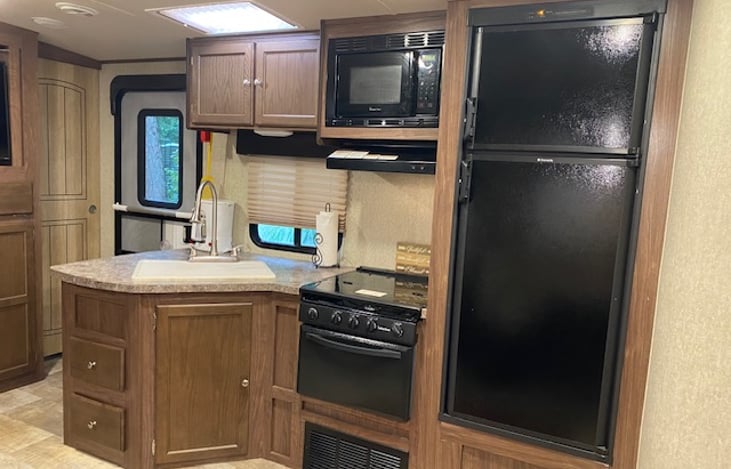 Kitchen with fridge, three burner stove, microwave and sink