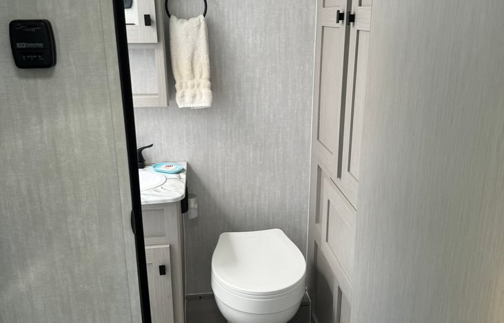 Fully equipped bathroom with toilet, sink, shower, and lots of storage