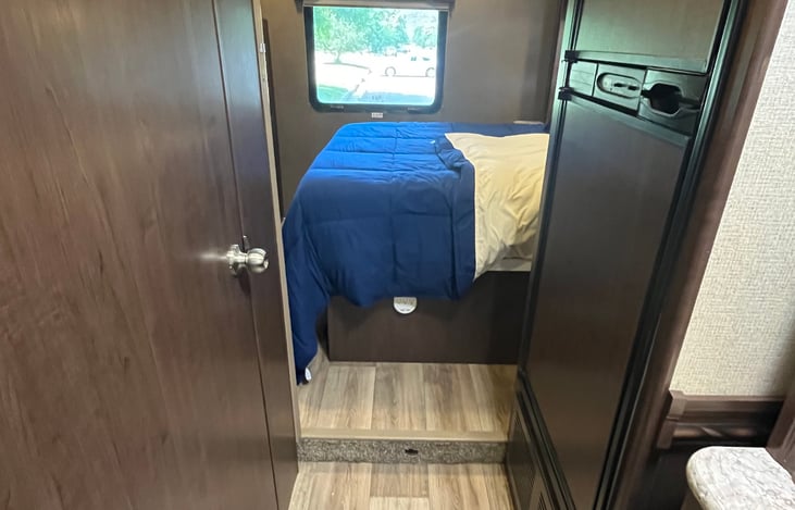 Picture showing the back of the RV, showing the bathroom (on the left) and the queen bed in the back.