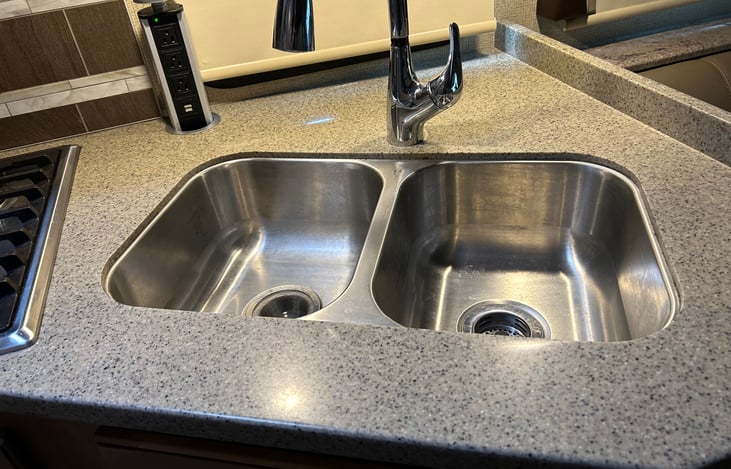 There is a double stainless sink with a sprayer nozzle. Additionally there are several USB and 120 Volt outlets throughout the RV for charging your devices.
