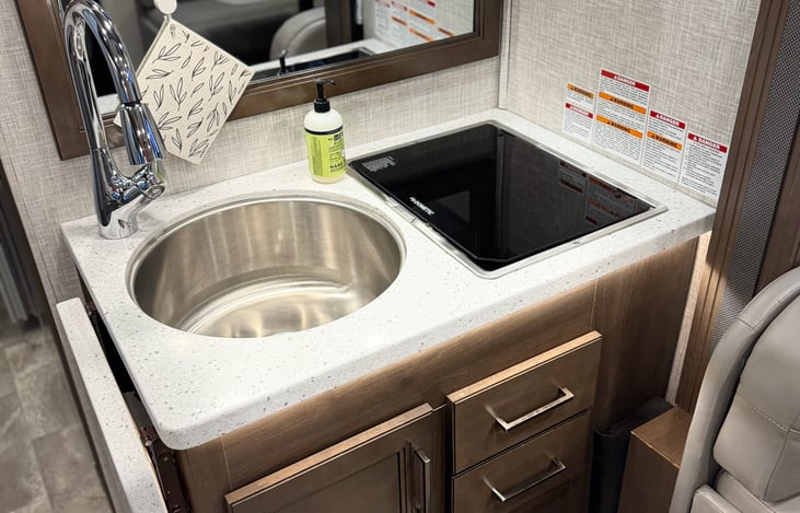 View of kitchen area with sink cover removed, cover down over stop top burner.