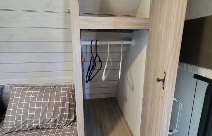 Closet with hangers on both sides of the bed