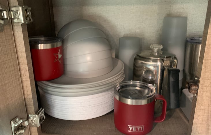 Plastic plates, bowls, cups and metal percolator for coffee.
