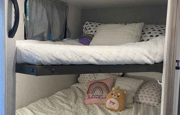 Double over double beds in rear of trailer beside bathroom.