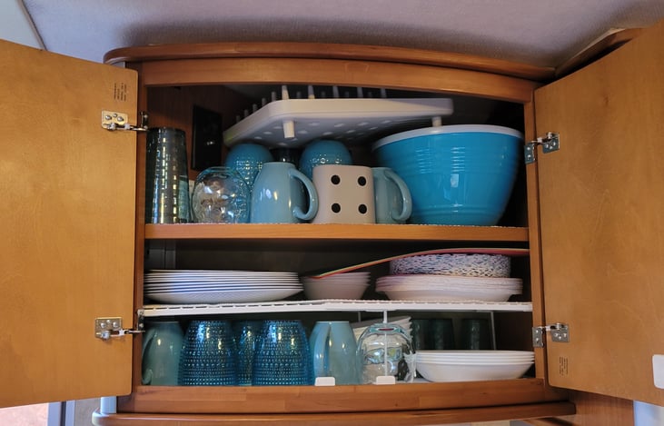 Fully stocked with dishes, coffee cups, glasses and paper products.