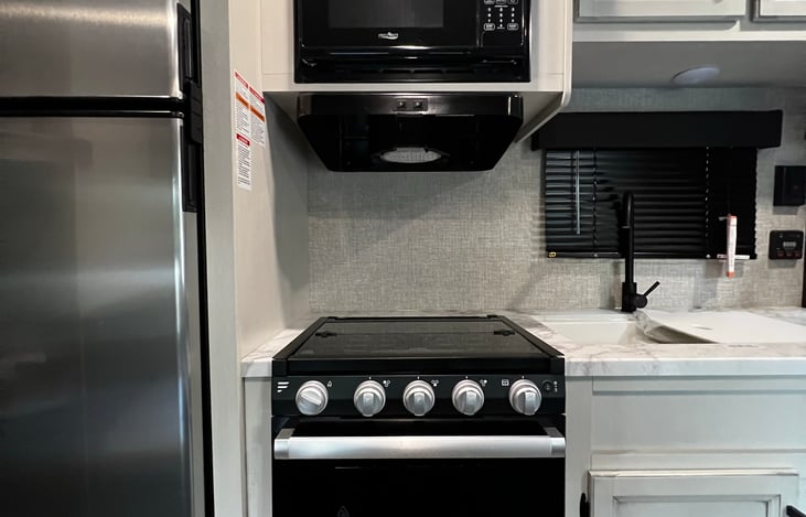 Kitchen w/ 3 burner stove, microwave, double sink, full size fridge and many cabinets.