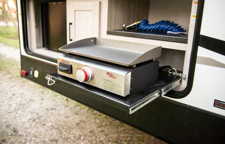 Convenient outdoor kitchen features a mini-fridge and slide-out propane griddle.