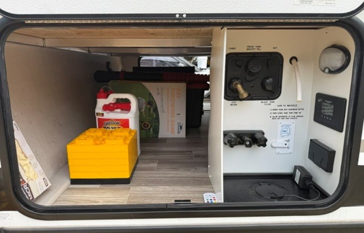 Front Left Outside Storage and Water Bay. Includes Bug spray, toy throwing axe game for kids, ect..