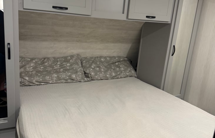 Queen sized bed in the private bedroom with plenty of storage around the bed including 2 closets, overhead storage, and under the bed storage