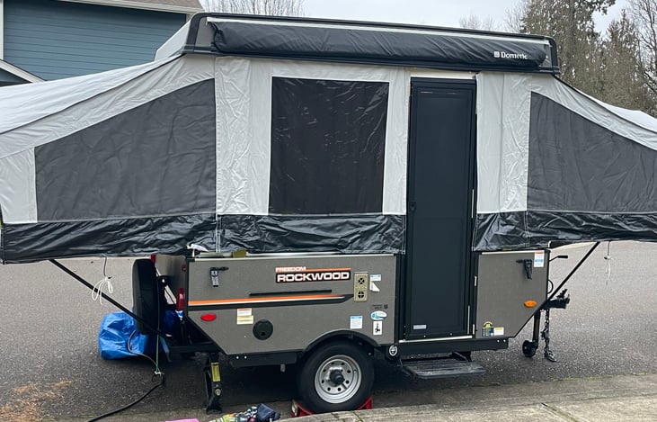 Small lightweight pop up camper has a sturdy door with screen, awning, and place for removable table/grill!