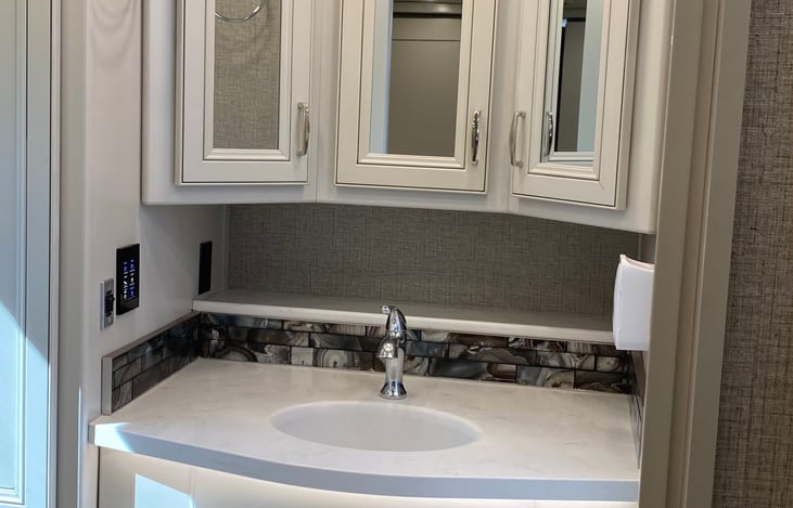 Sink area in rear bathroom, full size shower is on the right side just out of the picture. Storage under the sink and three compartment medicine cabinet about the sink.