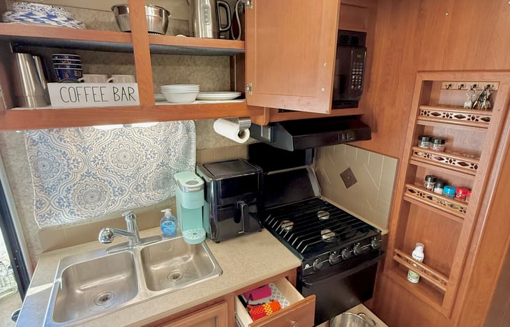Kitchen and appliances. Gas stove/oven, microwave, air fryer, Keurig, water kettle, dishes, pot, pan, strainer, utensils.