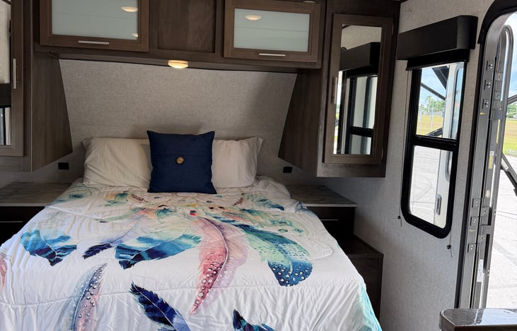 Plush front queen bed with cozy comforter, private accent wall, and built-in bedside storage.