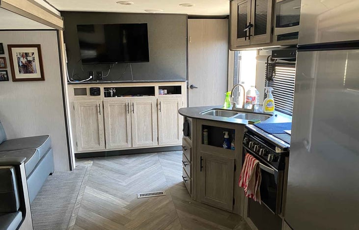 Couch, TV and media entertainment, storage, master bedroom door, main entrance, kitchen sink, upper and storage, microwave, range, oven and fridge.