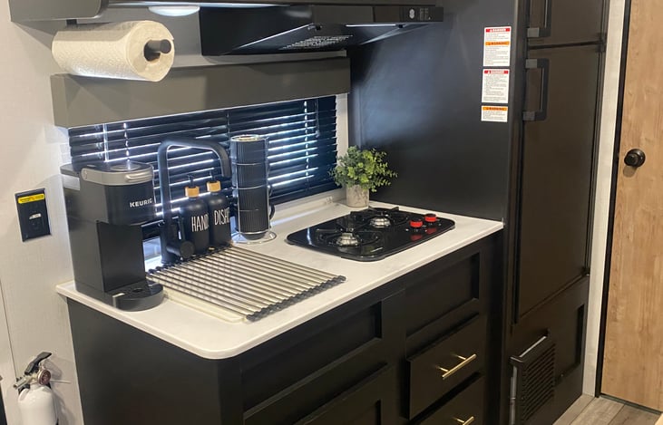 Kitchen has a two burner stove top, sink, Keurig, coffee pods, coffee mugs, plates, bowls, cups, utensils, cookware, salt/pepper, lighter, flash lights, & can opener, etc.