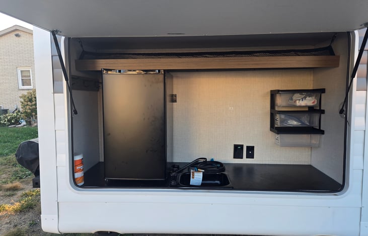 Outdoor kitchen with fridge, sink, and grill
