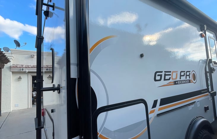 Back of camper with ladder , side door to outdoor fridge.