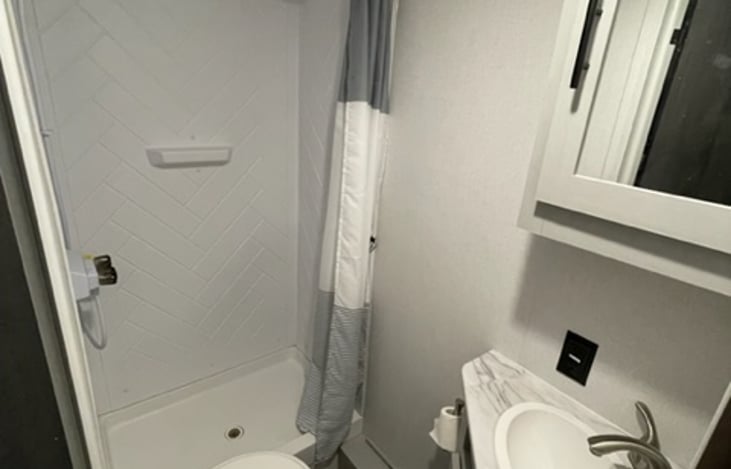 Bathroom with shower, toilet and sink. Medicine cabinet above the sink and cabinet below the sink to hold your bathroom supplies. We will supply RV safe toilet paper.
